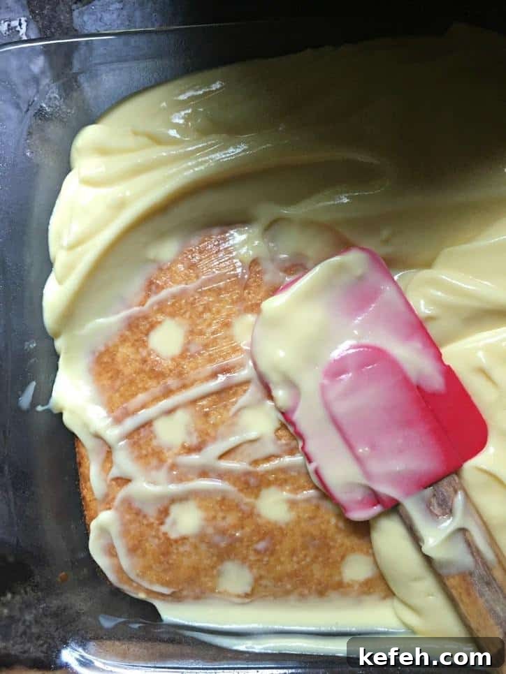 A photo of spreading the pudding onto the baked cake with holes poked into it