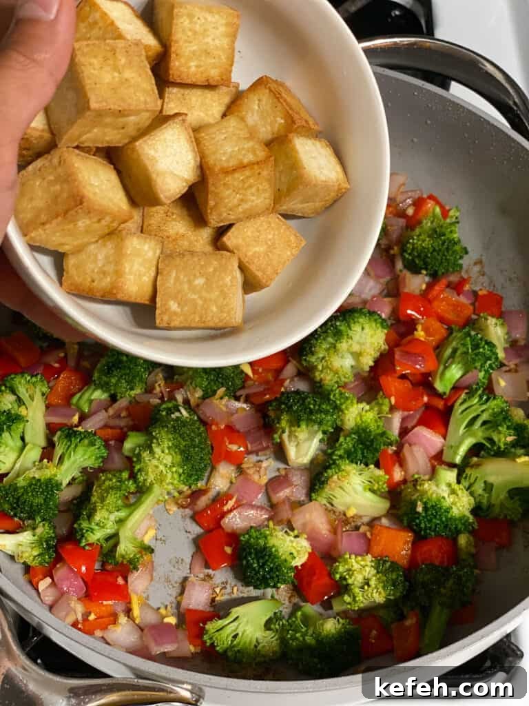Quick Teriyaki Tofu Stir-Fry with Crisp Veggies 5 process shot of adding bowl of cooked tofu to pan of veggies