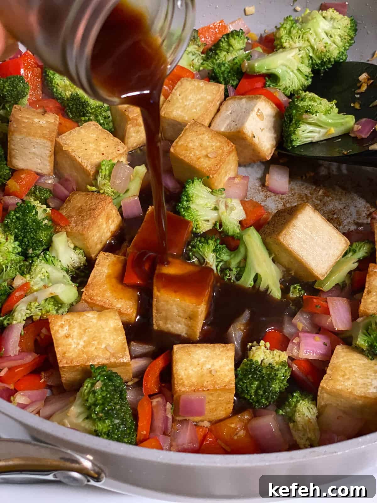 Quick Teriyaki Tofu Stir-Fry with Crisp Veggies 6 process shot of adding sauce to pan of tofu and veggies