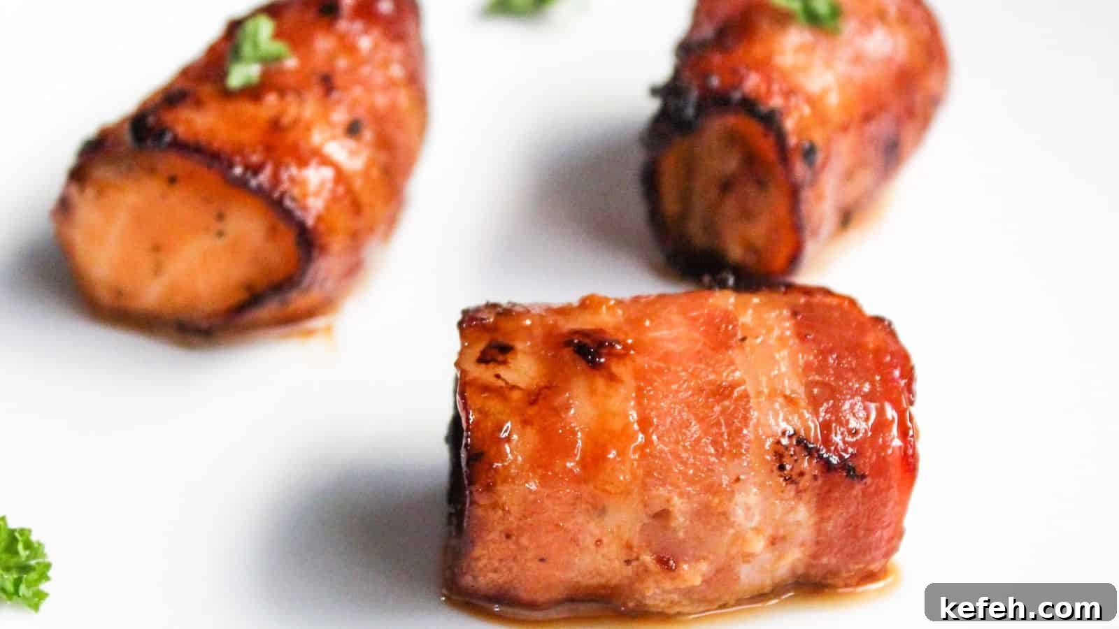 30 Seafood Recipes That Turn Weeknights Into a Vacation 12 Three pieces of bacon-wrapped salmon bites garnished with parsley on a white plate.