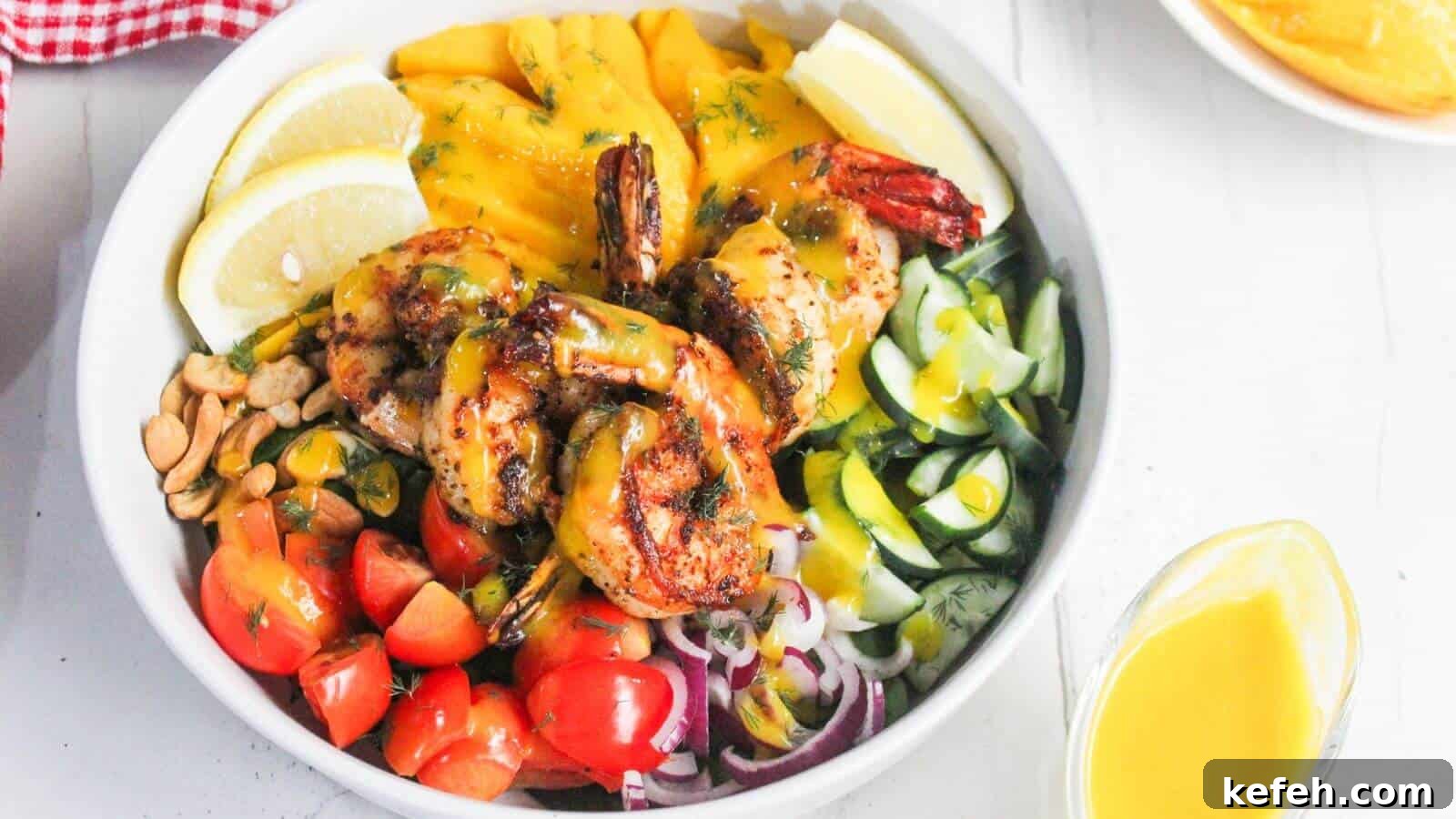 30 Seafood Recipes That Turn Weeknights Into a Vacation 13 A bowl with grilled shrimp, sliced mango, lemon wedges, cherry tomatoes, cucumbers, red onions, peanuts, and greens, topped with a yellow sauce.