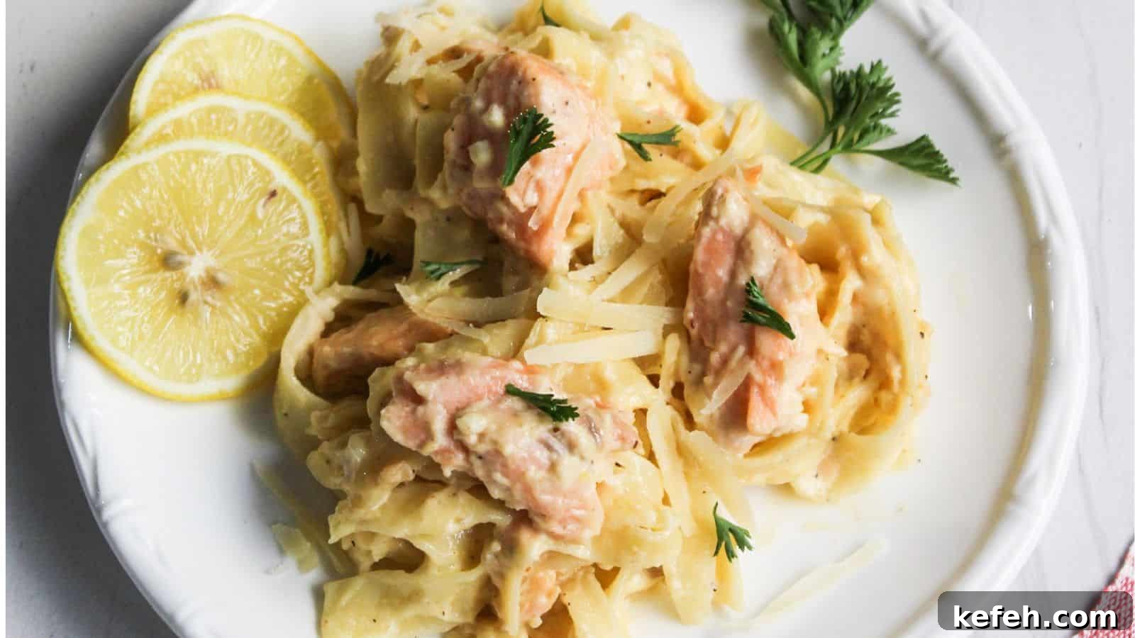 30 Seafood Recipes That Turn Weeknights Into a Vacation 24 Salmon pasta Alfredo served on a white plate with lemon.