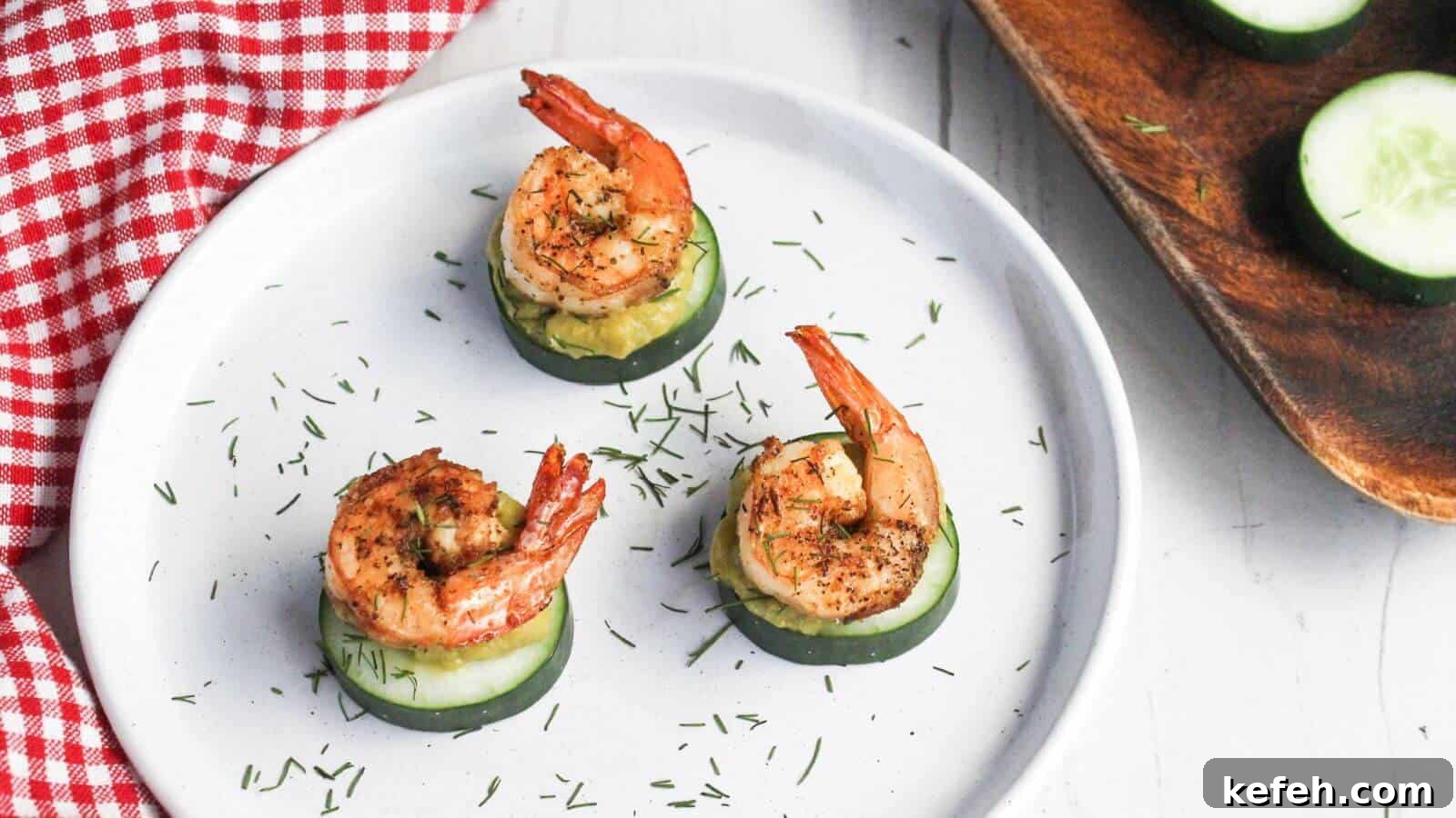 30 Seafood Recipes That Turn Weeknights Into a Vacation 27 Three grilled shrimp atop cucumber slices garnished with herbs on a white plate with a red checkered napkin partially in view.