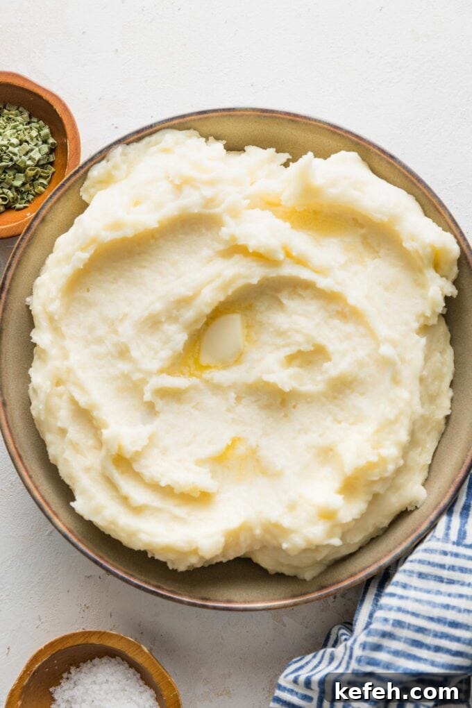 Large bowl of mashed potatoes served with extra butter.