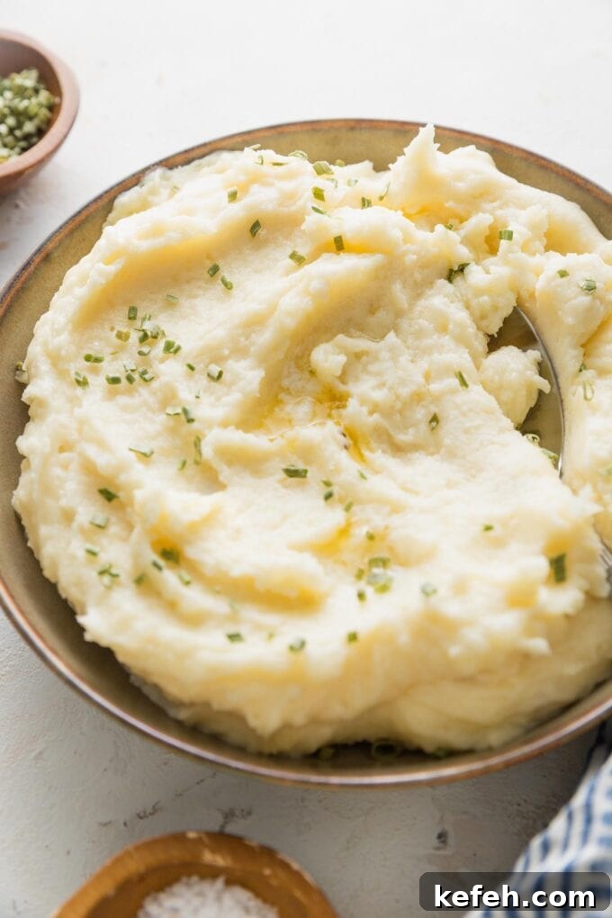 Bowl of make ahead mashed potatoes with extra melted butter and chives.