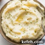 Bowl of creamy mashed potatoes with butter and chives.