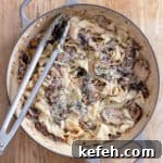 A large skillet of mushroom pappardelle with grated parmesan on top.