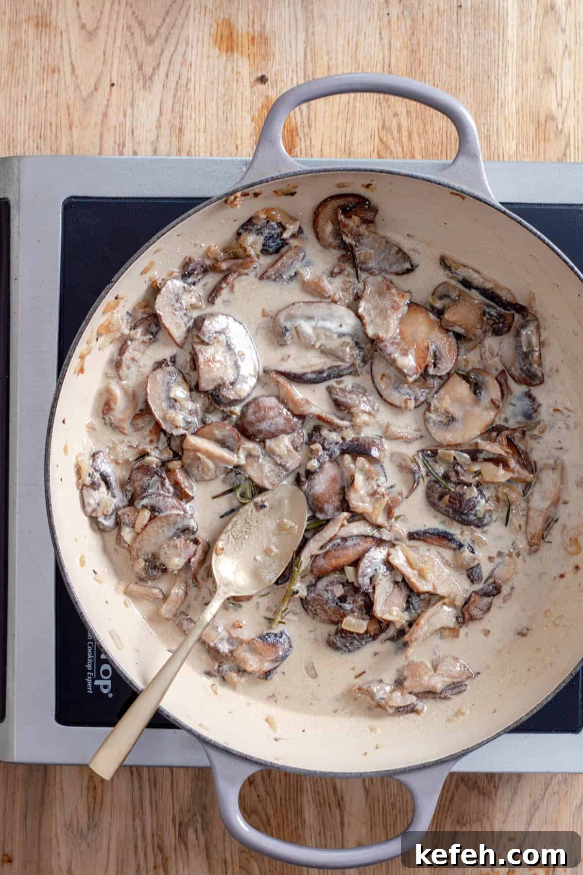 A mushroom sauce cooking in a large skillet with white wine, cream and herbs.