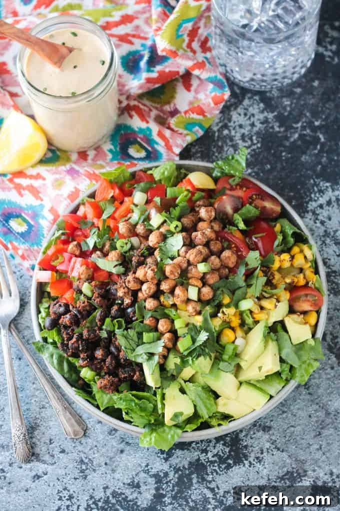 Big plate of salad with avocado, black beans, red peppers,tomatoes, corn, and crunchy roasted chickpeas.