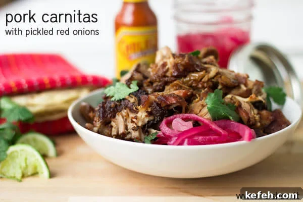 Delicious carnitas with pickled red onions and cilantro on a wooden cutting board.