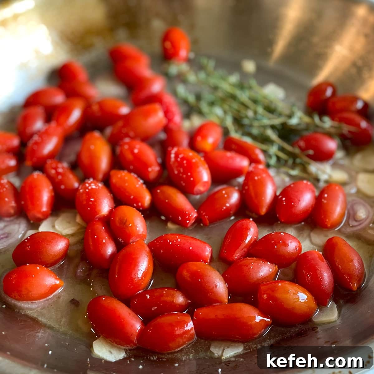 Fresh cherry tomatoes and thyme sit in a stainless steel pan with sliced garlic, sliced shallots, lemon juice, white wine, and salt.