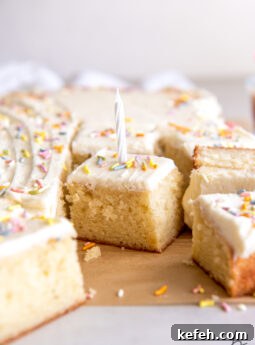 slice of vanilla sheet cake with vanilla frosting sprinkles and white birthday candle