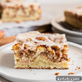 slice of honey bun cake on a plate showing layers of cinnamon brown sugar inside.