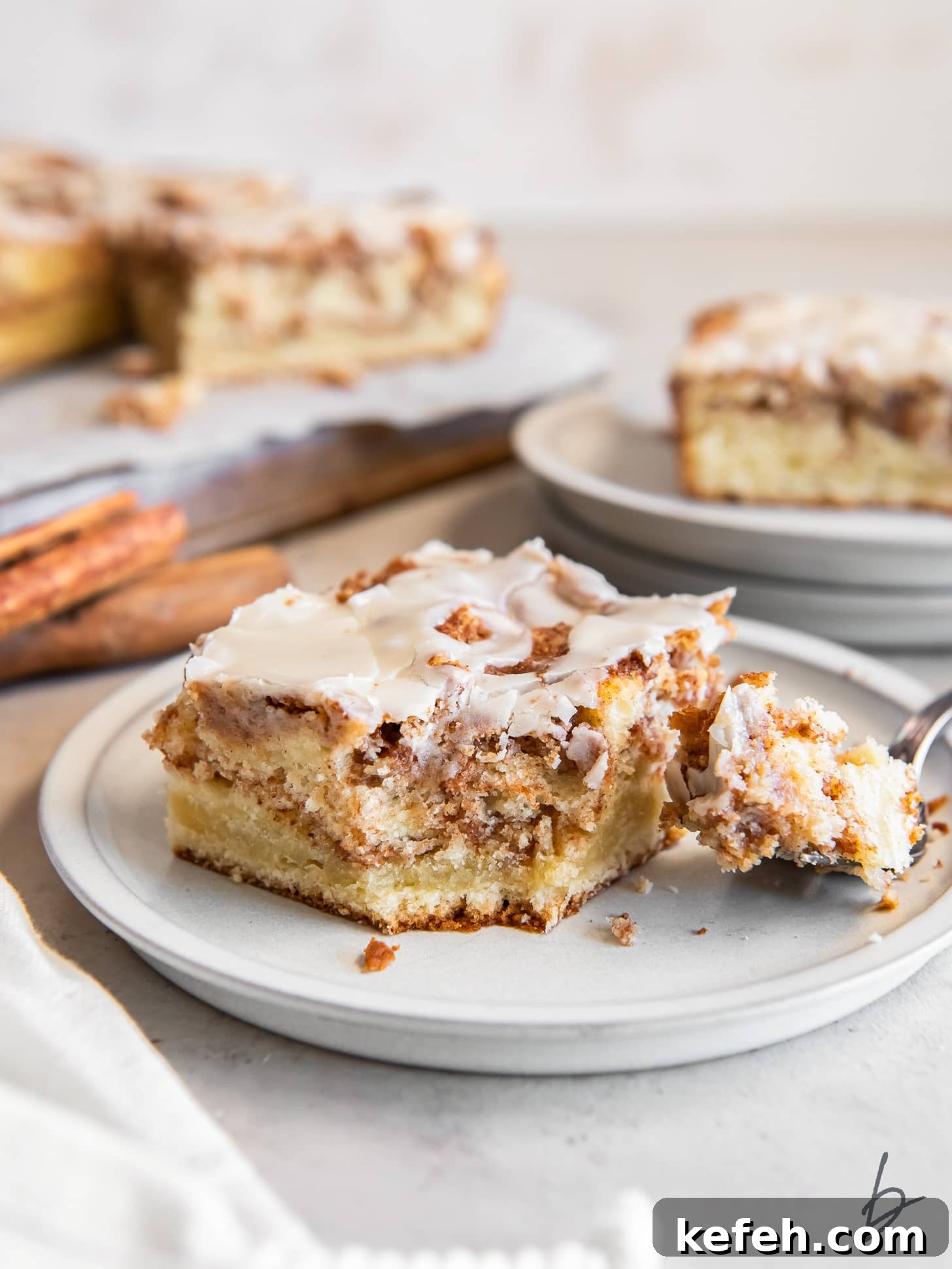 slice of moist honey bun cake on a plate with a fork holding a slice.