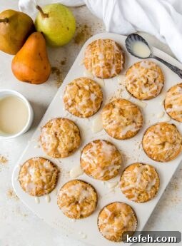 glazed ginger pear muffins in a muffin tin; pears next to muffin tin