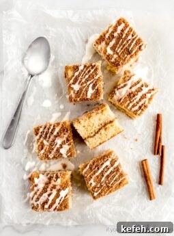 coffee cake square on parchment paper with vanilla glaze. Cinnamon stick and icing spoon