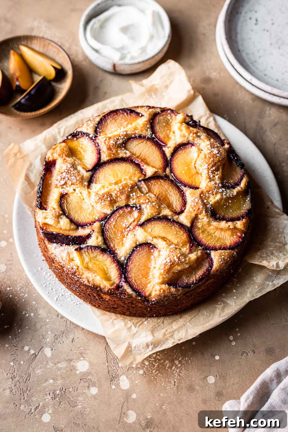 A baked plum and yogurt cake on a parchment lined platter.