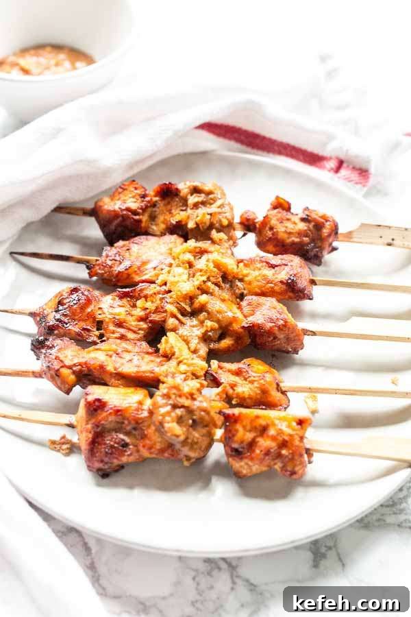 Crispy Air Fryer Chicken Satay with Peanut Dipping Sauce 7 Five pieces of Air Fryer chicken satay on a white plate served for dinner with some satay sauce.