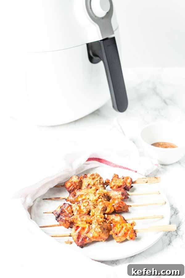 Crispy Air Fryer Chicken Satay with Peanut Dipping Sauce 8 Homemade chicken satay on a white plate. The satay is made in an Air Fryer with a grill pan and roasted to perfection.