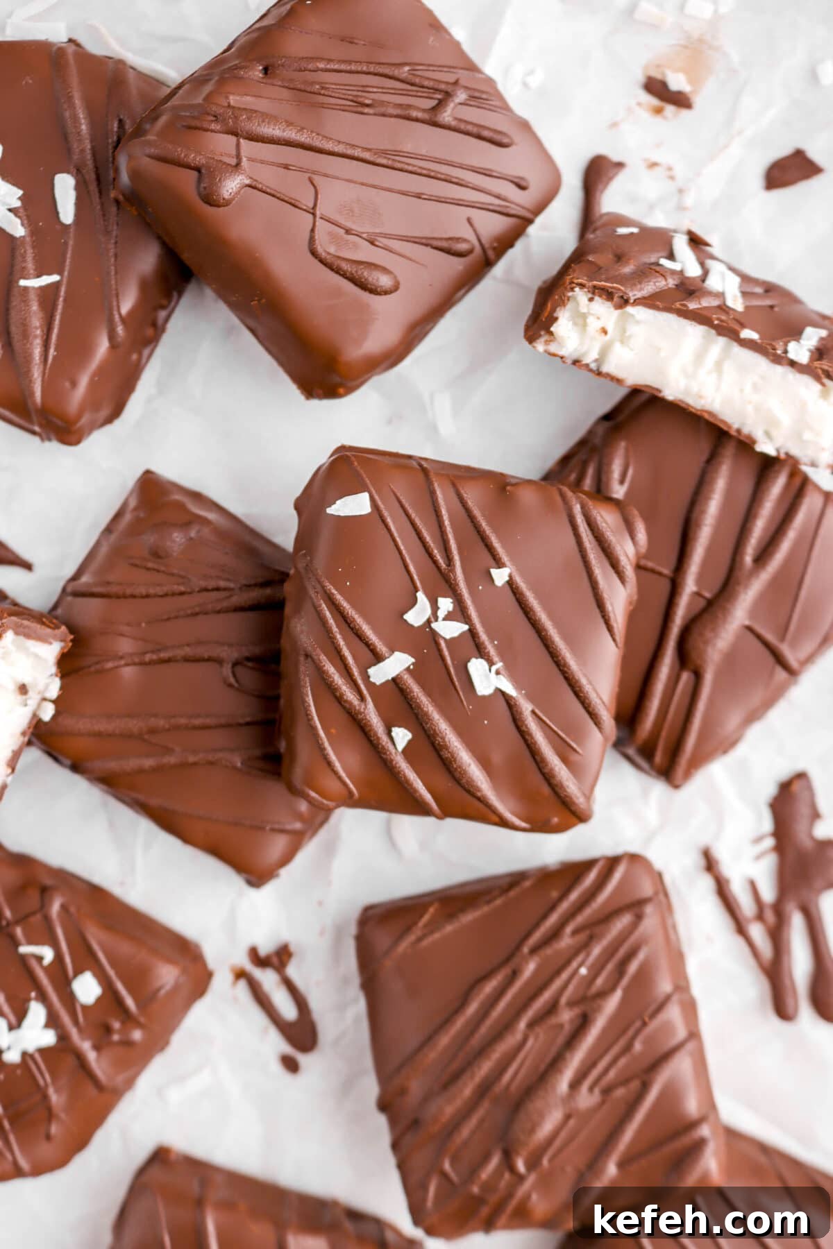 close up of square chocolates on parchment paper with one cut open.