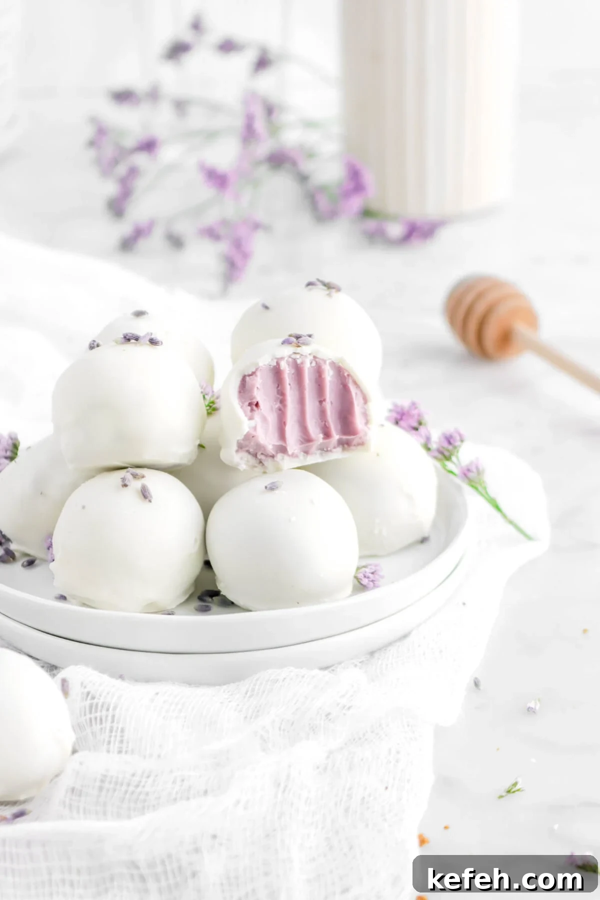 lavender white chocolate truffles on stack of white plates with bite missing