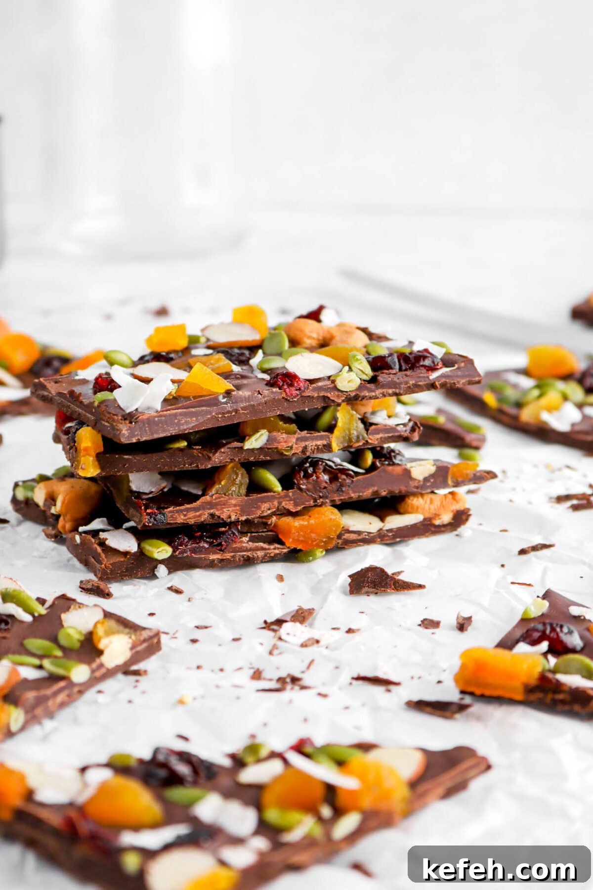 four stacked pieces of dark chocolate bark with empty glass behind