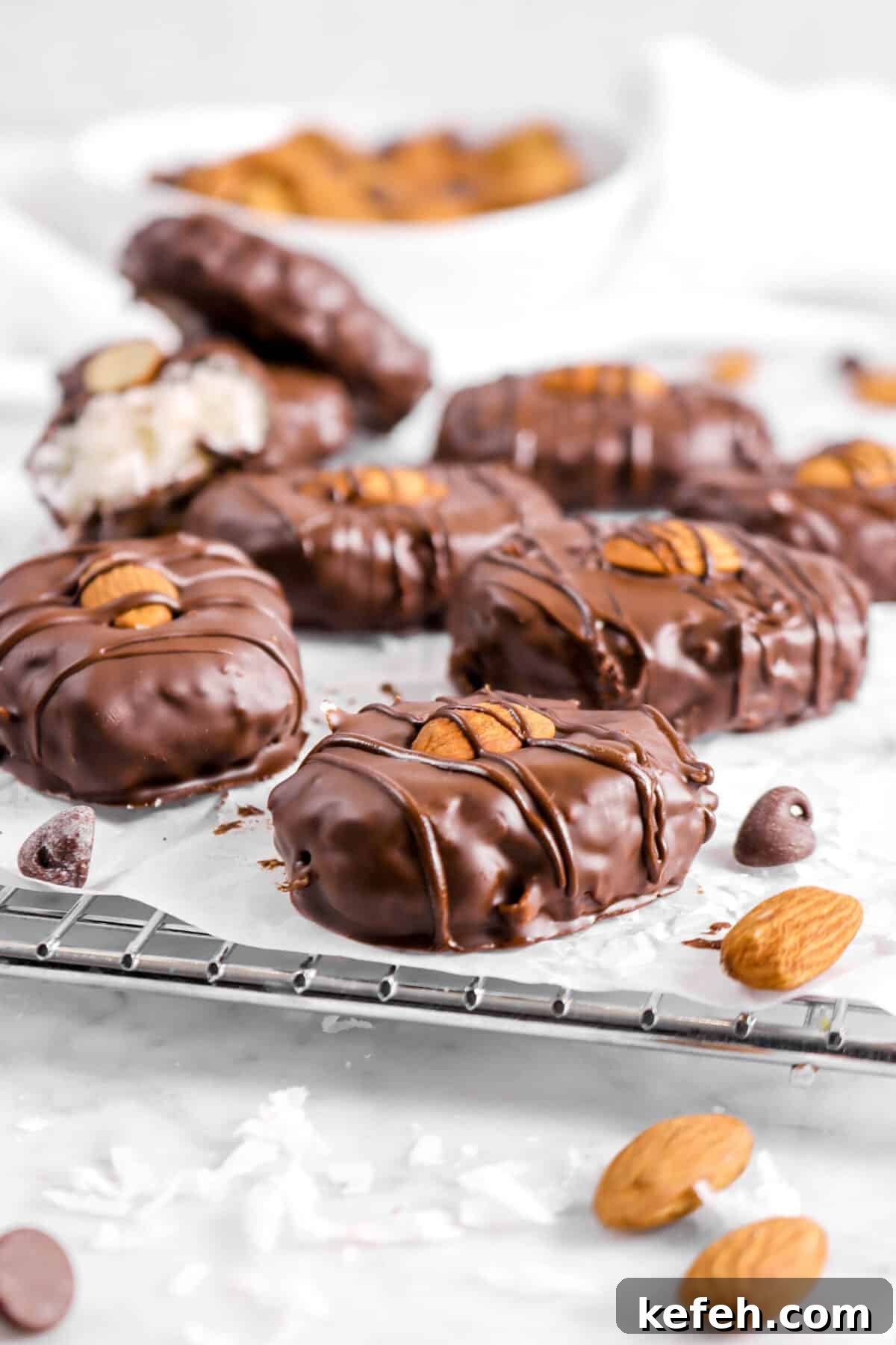 eight almond joys on a cooling rack with almonds and chocolate chips