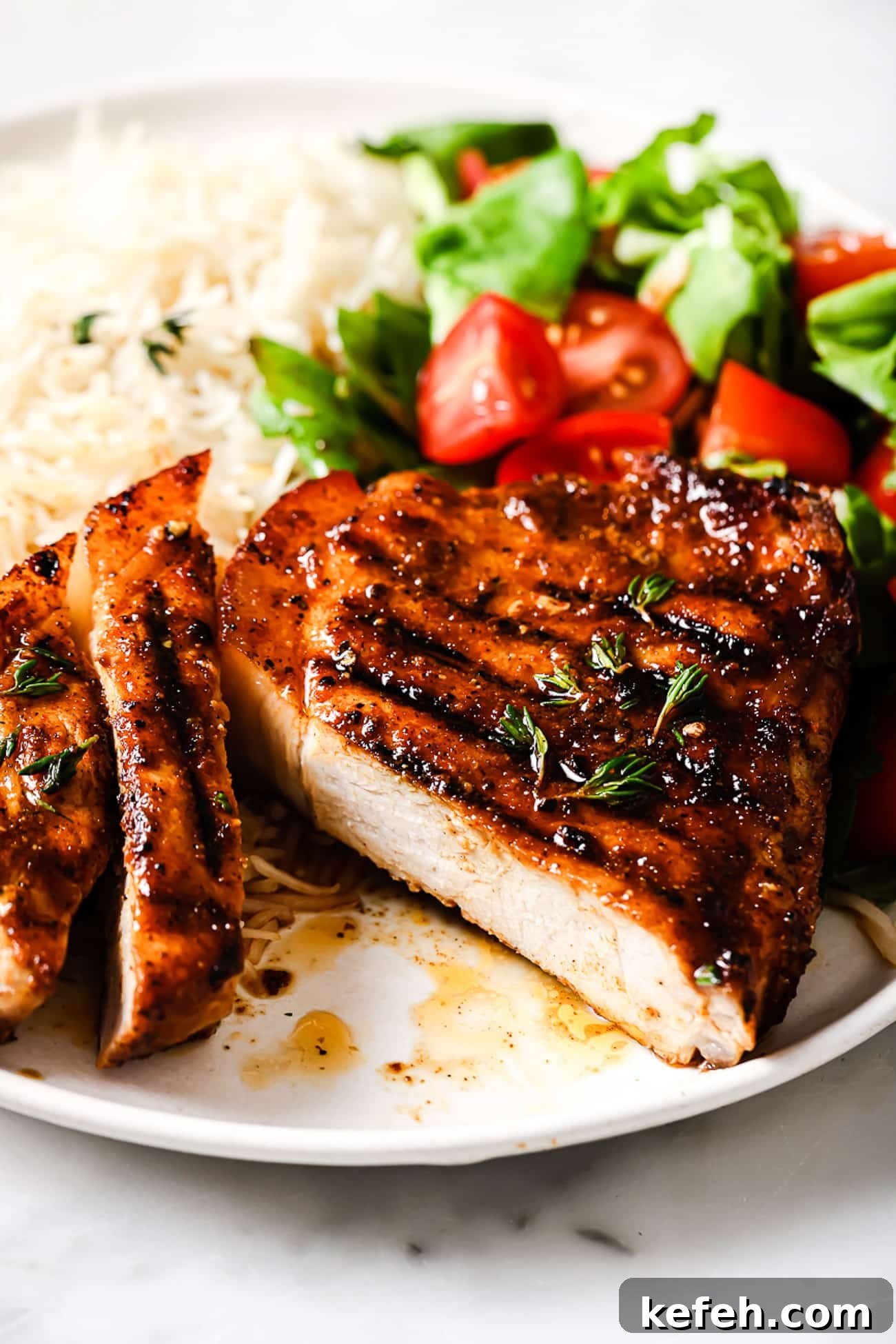 Grilled pork chops on a plate with white rice and a salad.