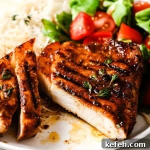 closeup of grilled pork chops on a plate with rice and salad