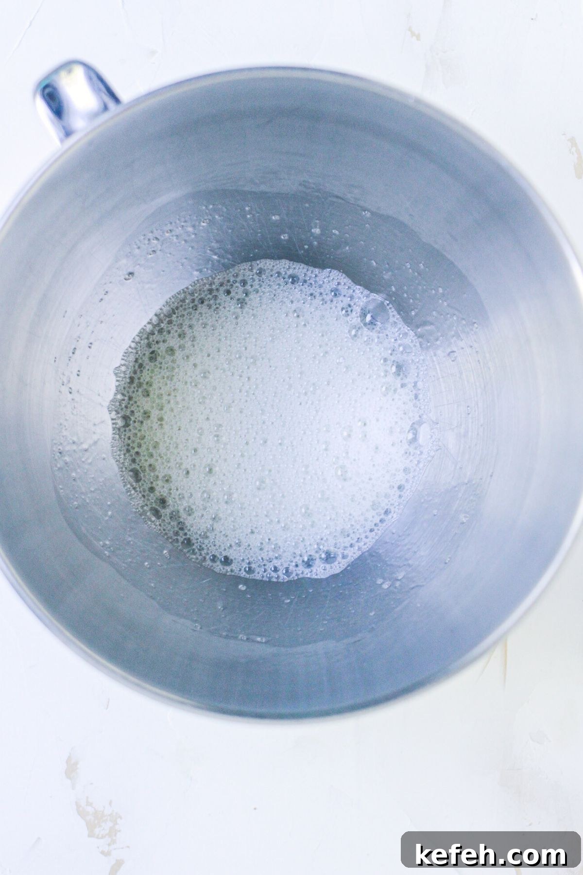 Egg whites in a silver mixing bowl, mixed until foamy. 