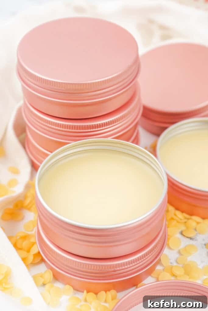 Stack of pink tins filled with finished dog paw balm, surrounded by beeswax pellets.