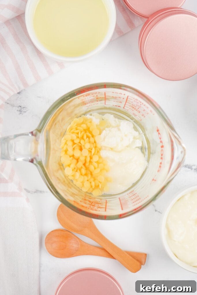 Beeswax pellets, coconut oil, and shea butter combined in a measuring cup, ready for melting.