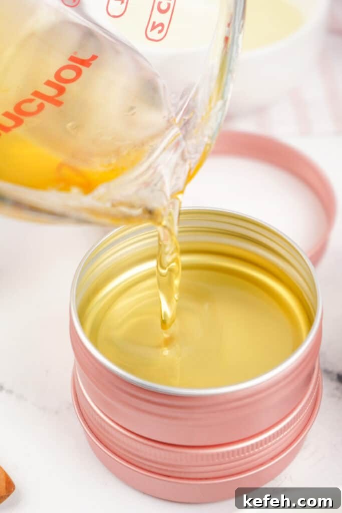 Hot melted balm being poured into a pink metal tin container.