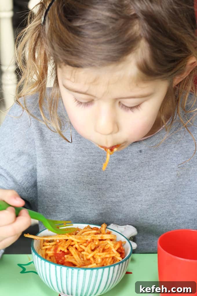 child eating a bowl of simple tomato spaghetti