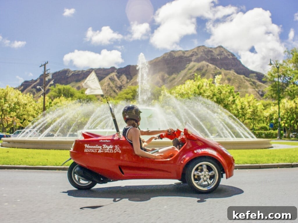100+ Waikīkī Activities: Local Favorites and Insider Tips 5 Red Scoot Coupe driving past a fountain with Diamond head in the background.