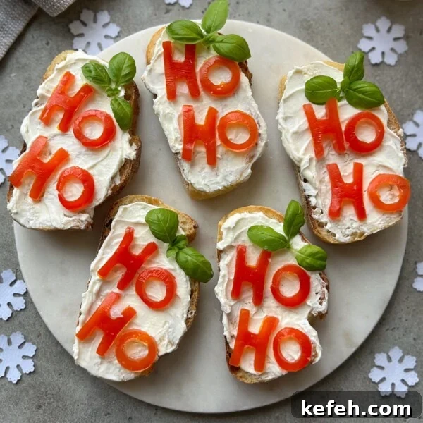 Christmas Party Appetizer Ideas to Impress Your Guests 11 Five slices of Christmas Bruschetta with cream cheese are topped with red bell pepper pieces spelling “HO HO” and garnished with basil leaves, arranged on a round plate surrounded by festive paper snowflakes.