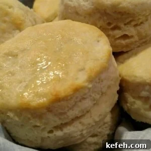 Buttermilk biscuits with a golden, flaky crust, stacked together in a basket.