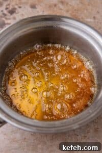 Homemade Caramel Coffee Syrup Recipe for Café-Quality Drinks 10 Homemade caramel coffee syrup bubbling in a small saucepan on the stovetop