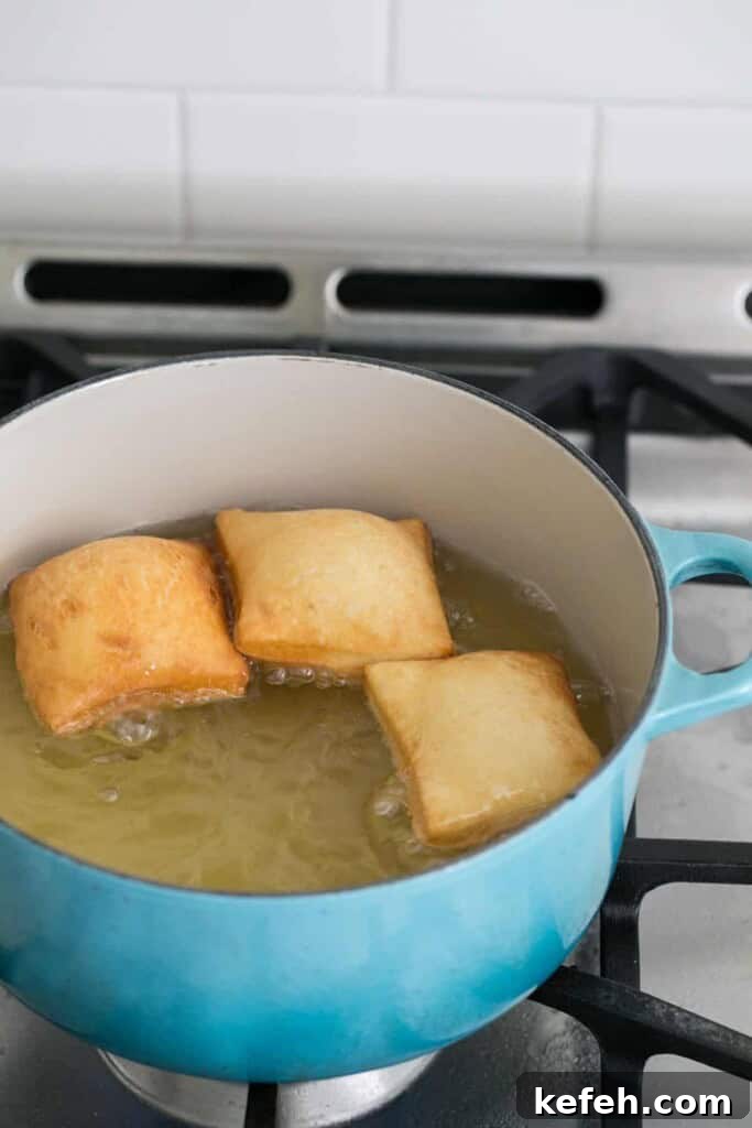 Authentic New Orleans Beignets Recipe for Perfect Cafe-Style Treats 6 Beignets cooking in oil.