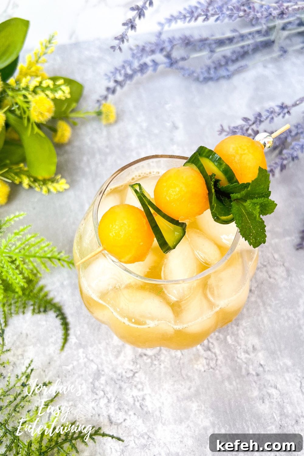 adding garnish of mint, cucumber ribbons and melon calls to a summer mocktail melon water also known as cucumber cantaloupe agua fresca