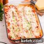 Classic Baked Manicotti with Ricotta and Marinara 14 Baked manicotti covered in tomato sauce, melted mozzarella cheese, and garnished with chopped parsley in a glass baking dish. The cheese is slightly browned and bubbly on top.