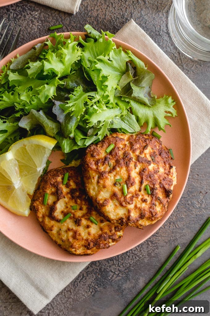 Salmon patties with fresh salmon served with greens and lemon slices.