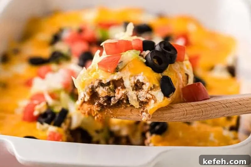 30 Ground Beef Dinner Recipes for Quick Family Meals 3 Taco Casserole being served on a wooden spoon.