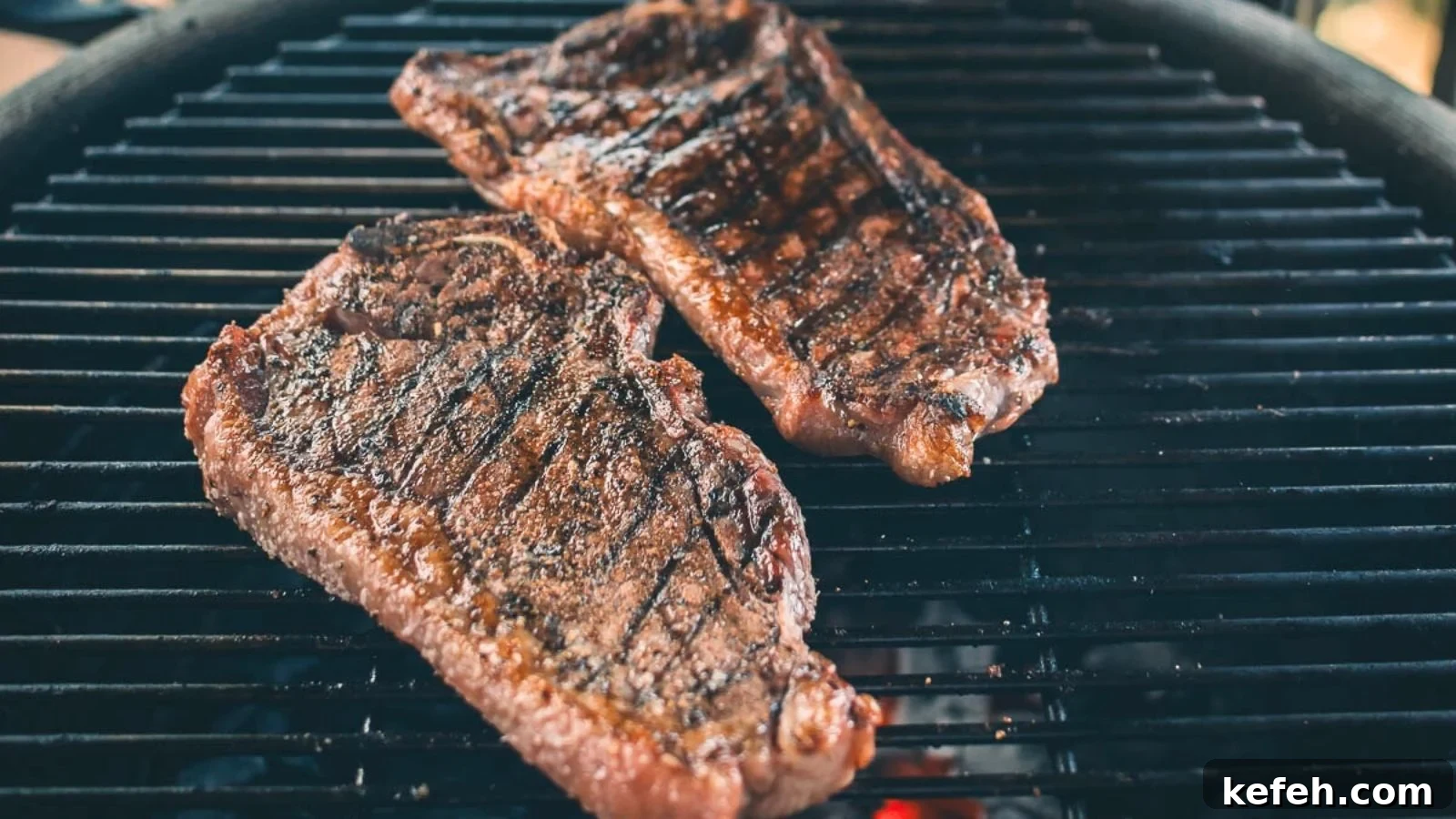 17 Budget-Friendly Steak Recipes to Feed a Crowd Without Breaking the Bank 9 Grilled strip steaks with bold grill marks and juices seeping onto the plate.