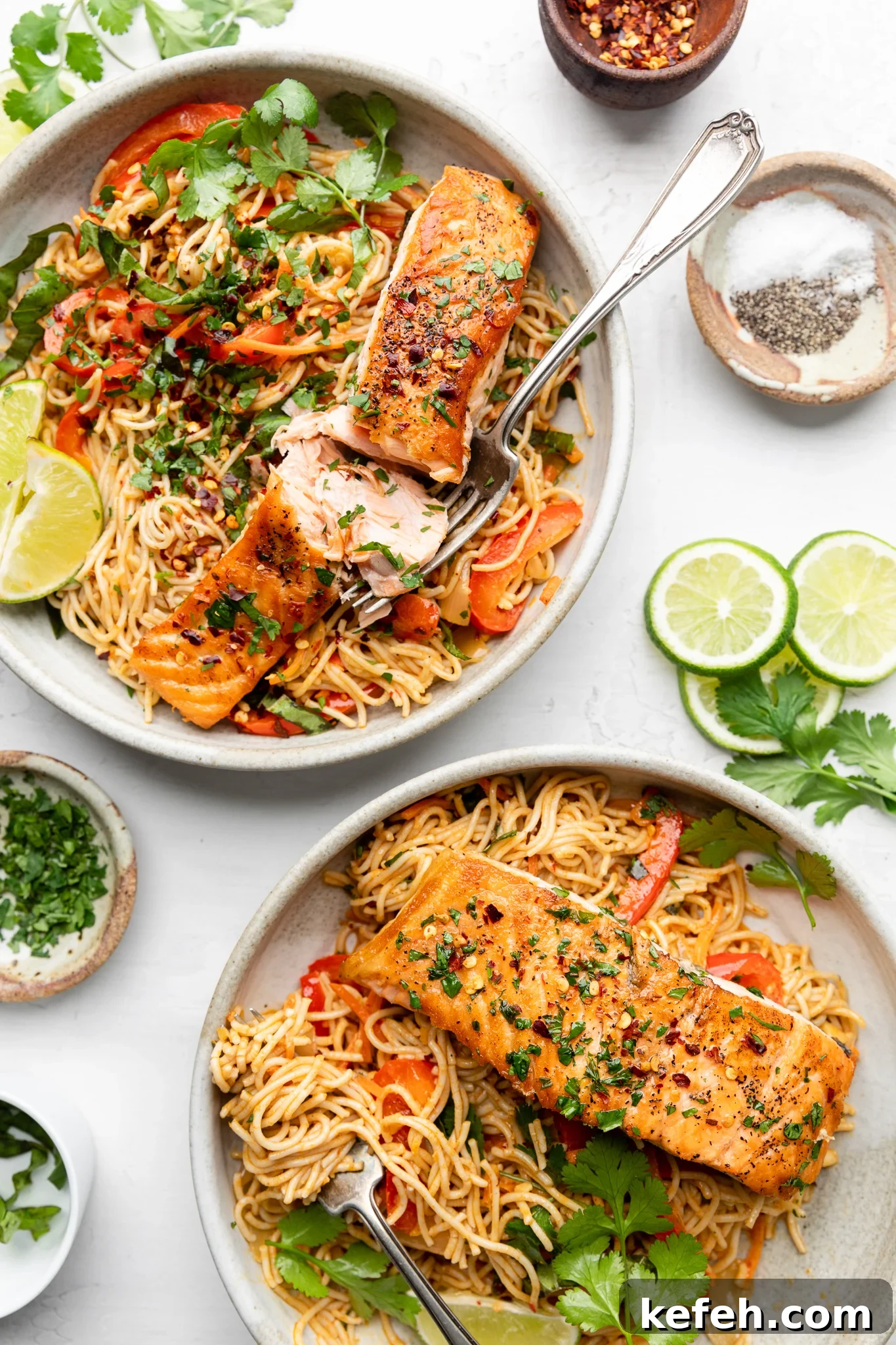 two plates with salmon on gluten free ramen noodles and garnished with lime wedges