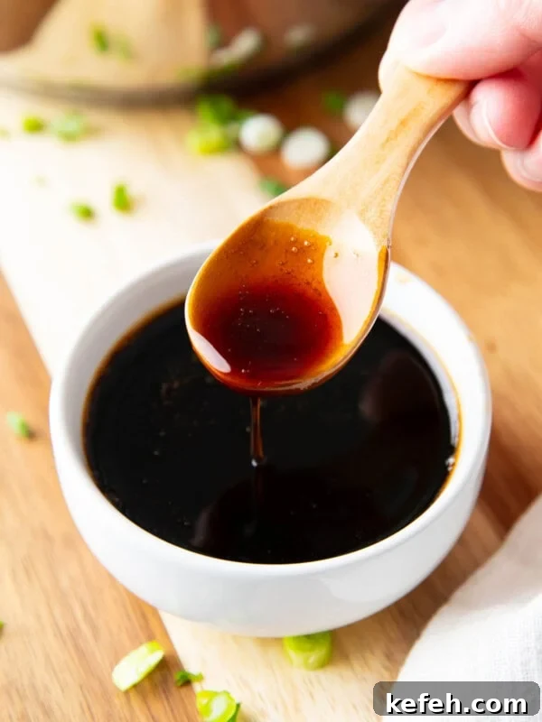 Someone spooning this thick eel sauce over a dipping bowl.