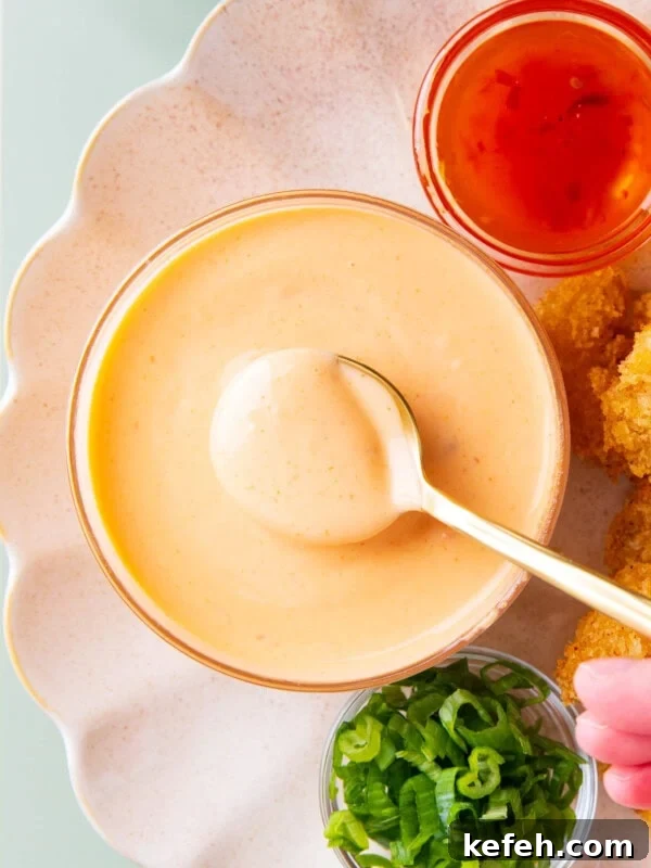 a person scooping up creamy bang bang sauce in a spoon
