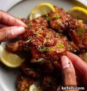 Korean Asian chicken wings with a sweet and tangy sauce garnished with green onions and a side of ranch dressing.