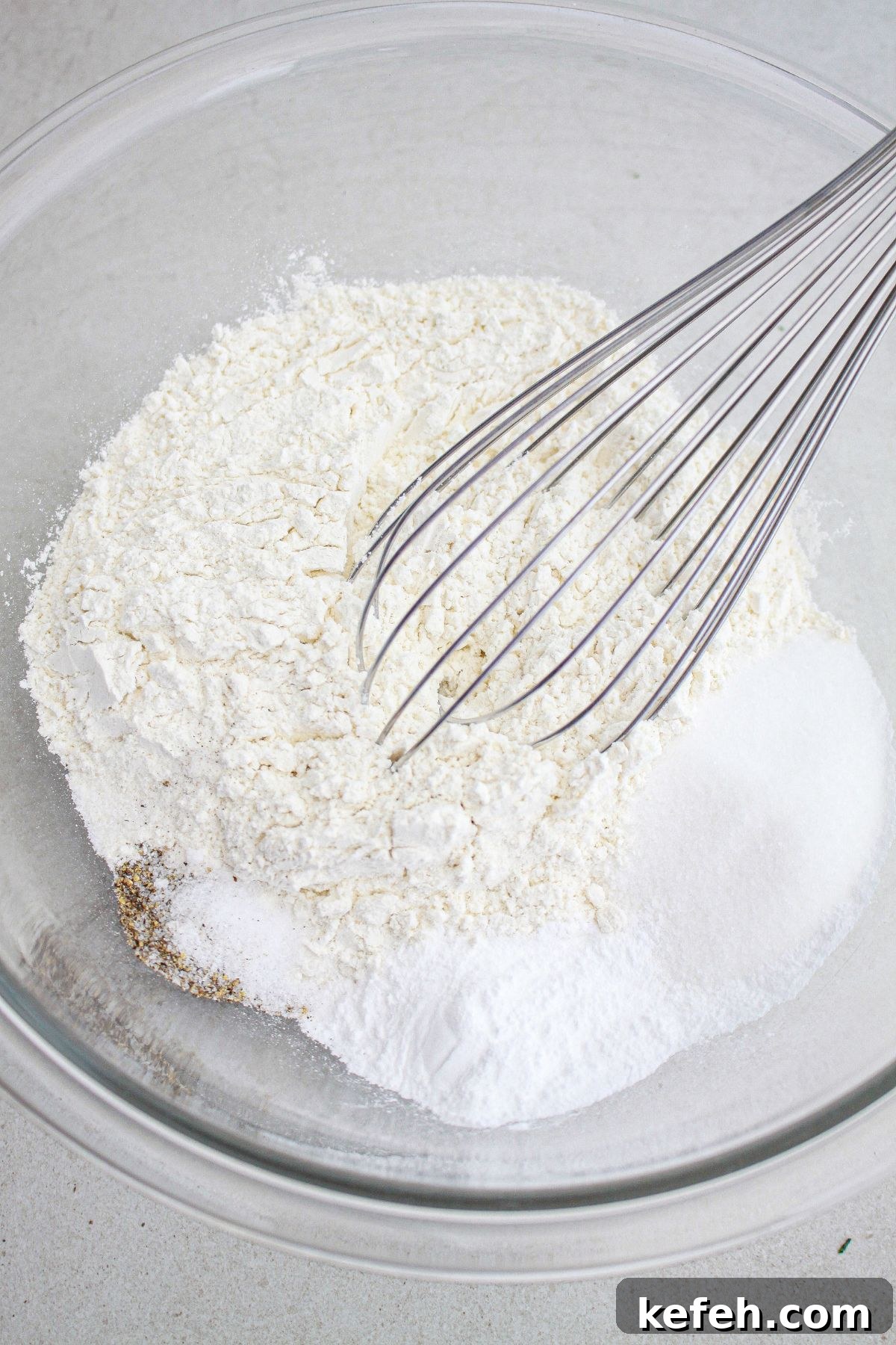 dry ingredients being whisked together in a glass mixing bowl.