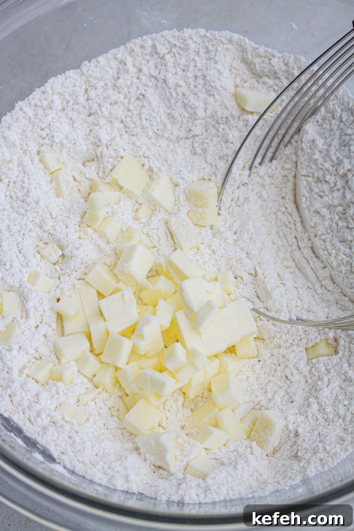 butter being added to dry ingredients with a pastry cutter.